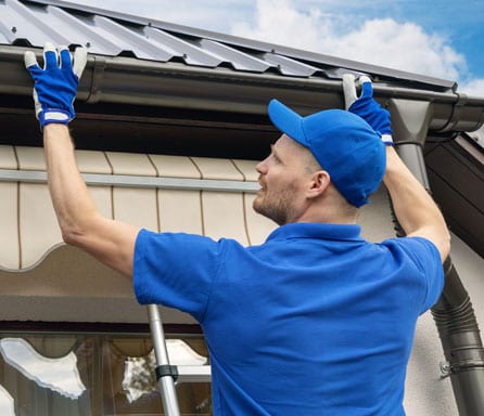 Ben Ross Roofing | Rock Hill, South Carolina | Man in blue shirt and cap replacing gutters on a house